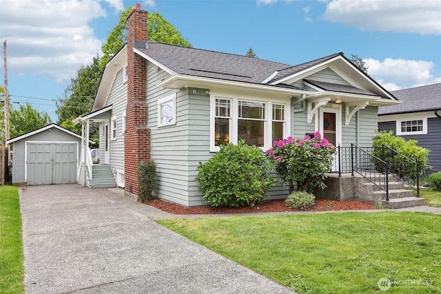 view of front of home featuring an outbuilding, a front yard, driveway, a detached garage, and a shed
