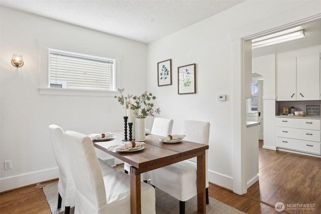 dining area featuring wood finished floors, baseboards, and a textured ceiling