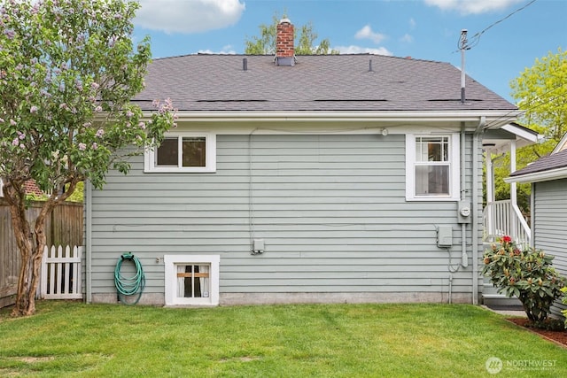 rear view of property featuring a chimney and a shingled roof