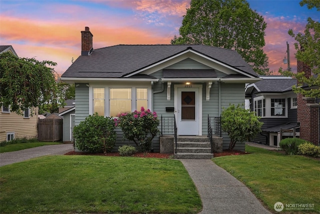 bungalow-style home with a chimney, a shingled roof, and driveway