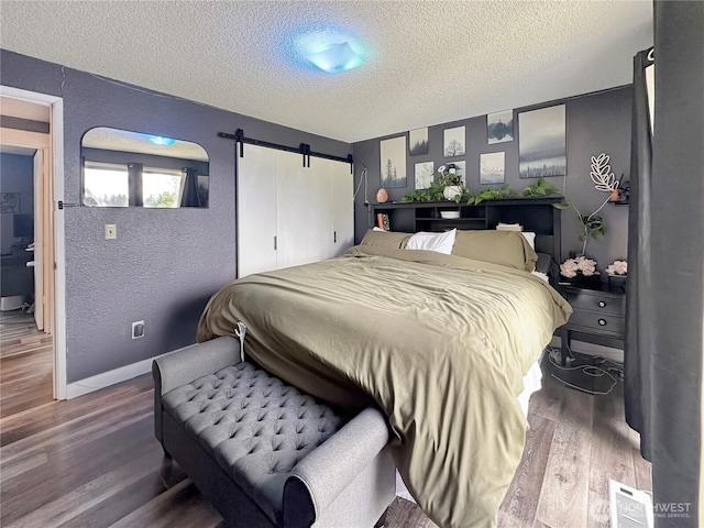 14914 20th Ave E, Parkland, WA 98445 - bedroom with a barn door, a textured ceiling, wood finished floors, and a textured wall
