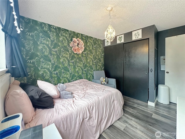 14914 20th Ave E, Parkland, WA 98445 - bedroom featuring an inviting chandelier, wood finished floors, wallpapered walls, a closet, and a textured ceiling