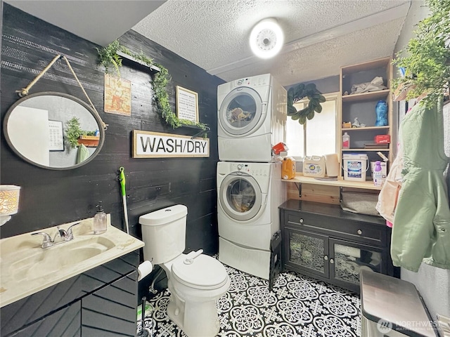 14914 20th Ave E, Parkland, WA 98445 - bathroom with toilet, vanity, a textured ceiling, stacked washer / drying machine, and tile patterned floors
