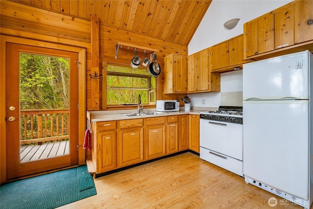 kitchen with a sink, light countertops, white appliances, and a wealth of natural light