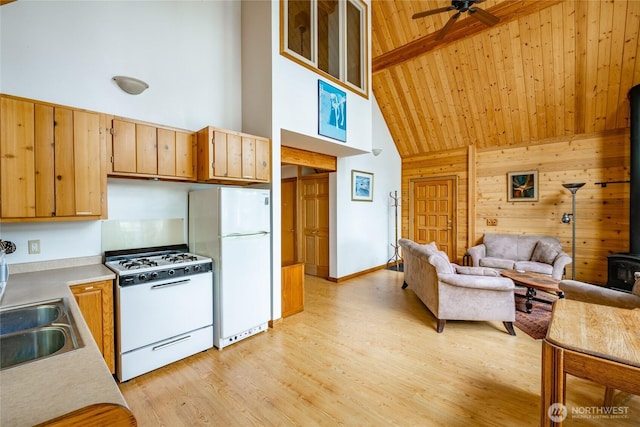 kitchen featuring a wood stove, white appliances, open floor plan, high vaulted ceiling, and a ceiling fan