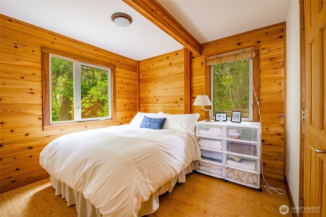 bedroom featuring multiple windows, beam ceiling, and wood finished floors