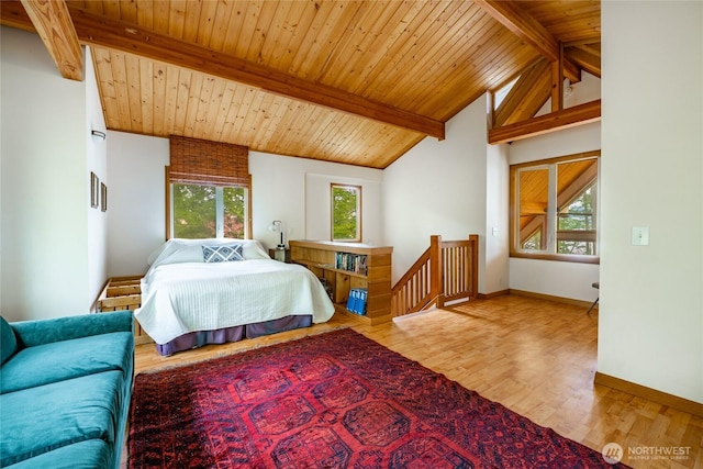 bedroom with baseboards, lofted ceiling with beams, multiple windows, and wood finished floors