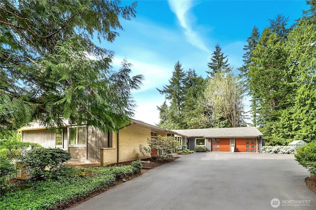 single story home with brick siding, an attached garage, and aphalt driveway