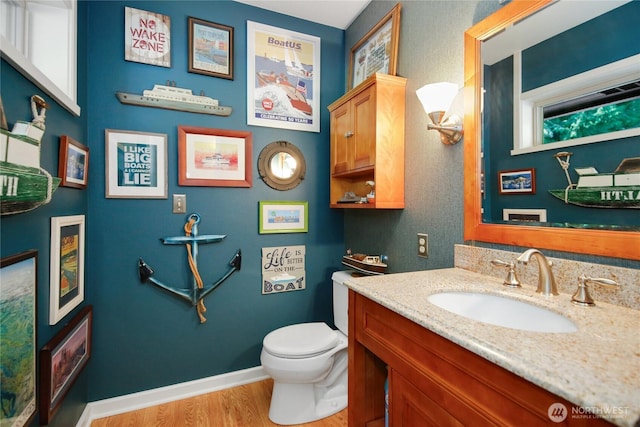 bathroom featuring baseboards, wood finished floors, vanity, and toilet