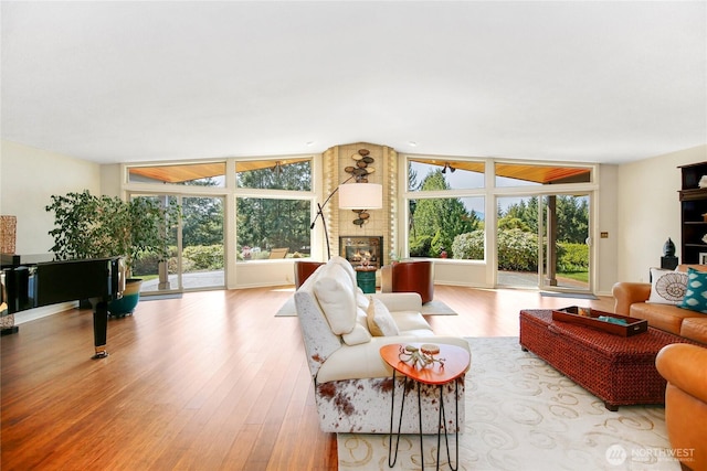 living room featuring wood finished floors, a brick fireplace, and lofted ceiling