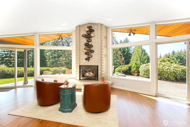 living room featuring wood finished floors, a brick fireplace, and baseboards