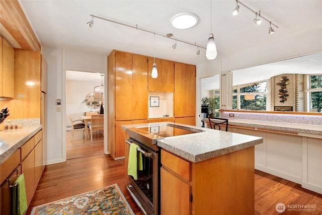 kitchen featuring stainless steel electric range, track lighting, wood finished floors, and a kitchen island