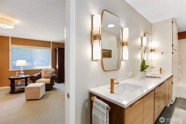 bathroom with a tub, baseboards, a sink, and double vanity
