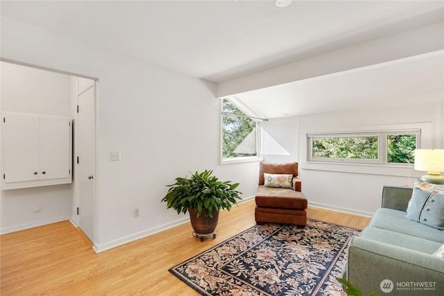 living area with light wood-type flooring, vaulted ceiling, and baseboards