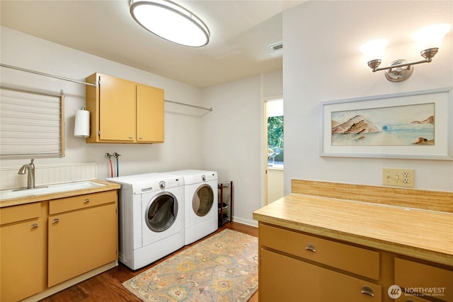 laundry room featuring dark wood finished floors, washer and dryer, cabinet space, and a sink