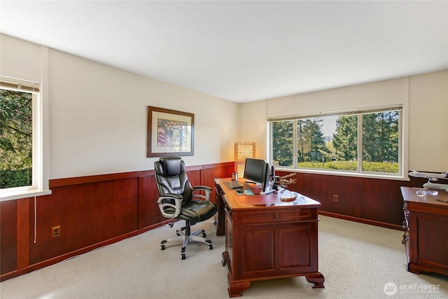 home office featuring a wainscoted wall, light carpet, and wood walls