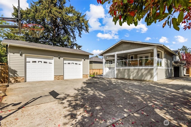 single story home featuring stairway, concrete driveway, covered porch, an outbuilding, and a garage