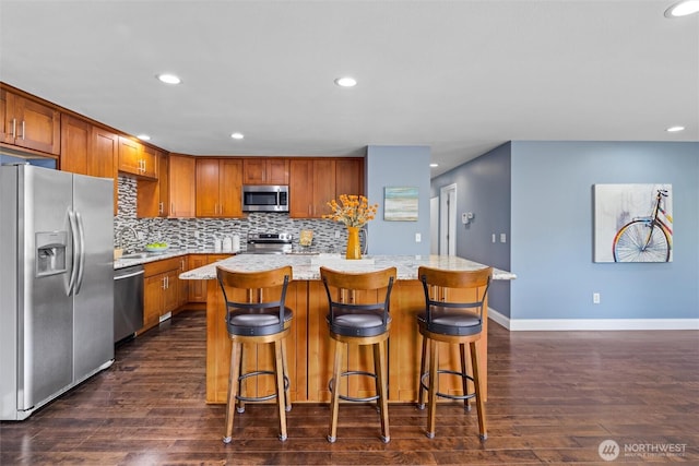 kitchen featuring recessed lighting, dark wood-style floors, backsplash, a center island, and appliances with stainless steel finishes