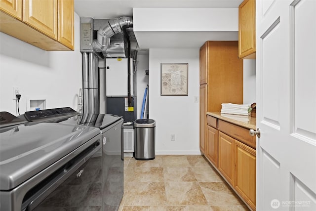 laundry room featuring baseboards, cabinet space, stone finish floor, and independent washer and dryer