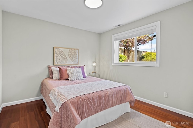 bedroom with baseboards, wood finished floors, and visible vents