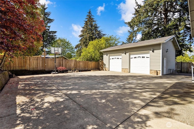 garage with concrete driveway and fence