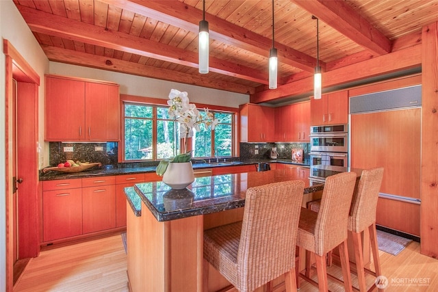 72 Thunderbird Trl, Orcas Island, WA 98280 - kitchen with built in fridge, stainless steel double oven, wood ceiling with exposed beams, light wood-type flooring, and tasteful backsplash