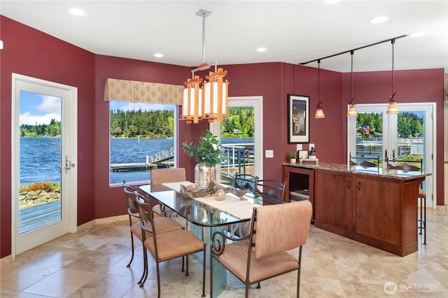 dining space with recessed lighting, a water view, and a healthy amount of sunlight