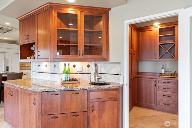 kitchen featuring a sink, open shelves, backsplash, and light stone countertops