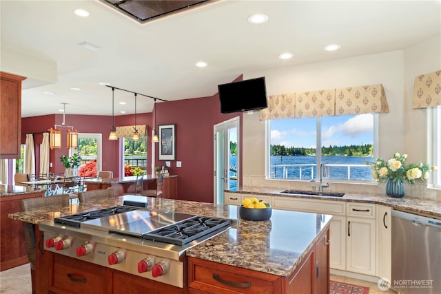 kitchen with light stone counters, a sink, stainless steel appliances, recessed lighting, and a kitchen island