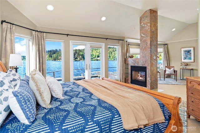 carpeted bedroom with a water view, vaulted ceiling, multiple windows, and a tile fireplace
