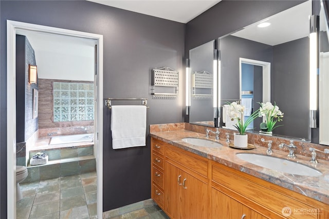 bathroom with a garden tub, a sink, stone finish flooring, and double vanity