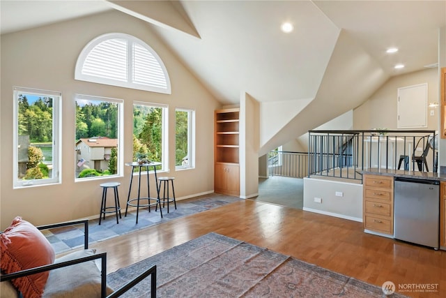 interior space with wood finished floors, baseboards, lofted ceiling, and an upstairs landing