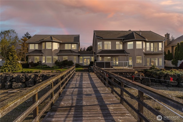 back of house at dusk featuring stucco siding