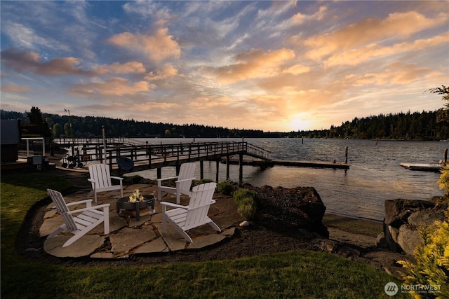 dock area featuring a water view, an outdoor fire pit, and a forest view