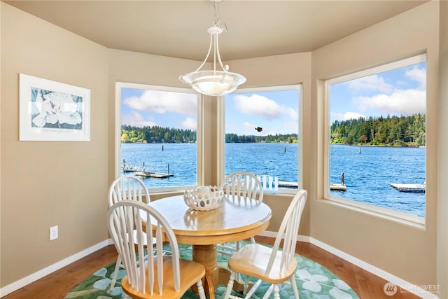 dining room featuring baseboards, a water view, and wood finished floors