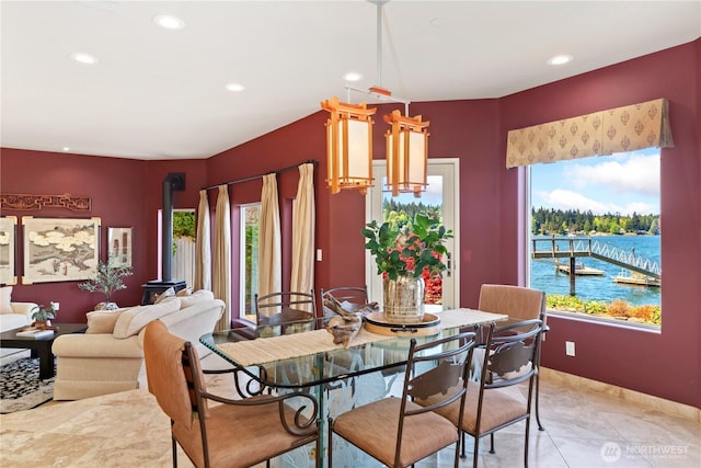 dining space with a water view, recessed lighting, baseboards, and a wood stove