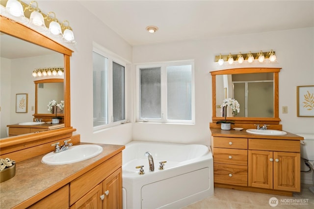 full bath featuring a stall shower, a bath, and two vanities
