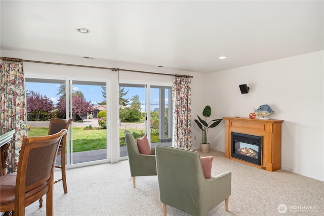 carpeted living area with a glass covered fireplace, recessed lighting, and baseboards