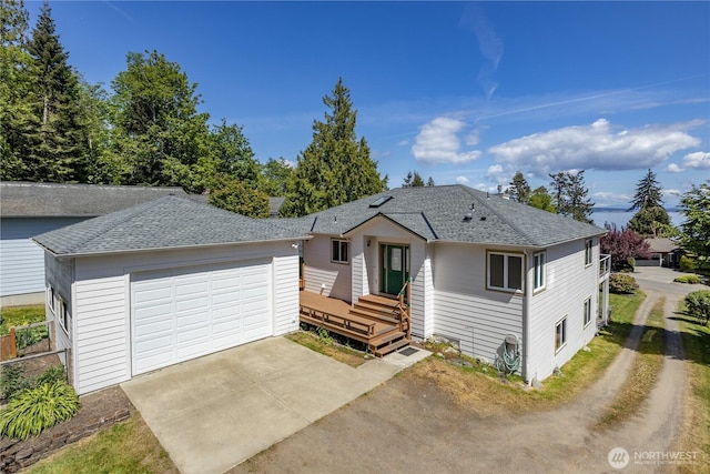 ranch-style home featuring driveway, a garage, and roof with shingles