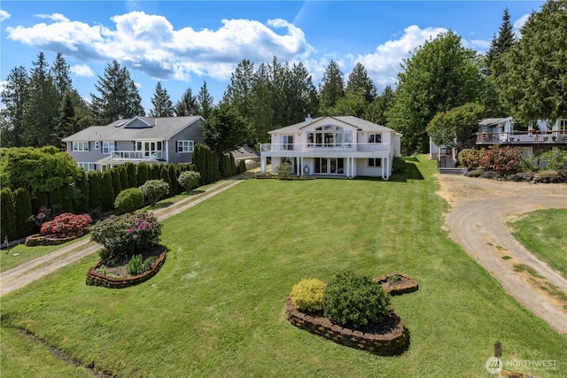 view of front of property with driveway, a front lawn, and view of wooded area