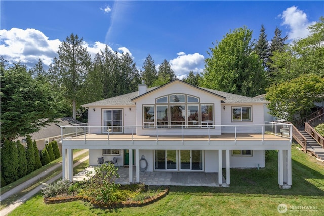 back of property featuring a lawn, a shingled roof, a chimney, and a patio