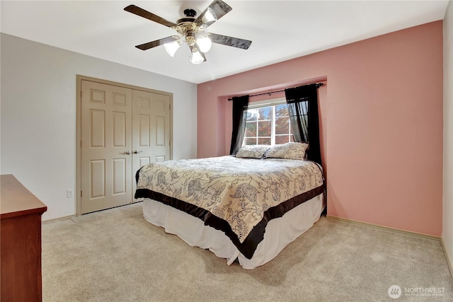bedroom featuring baseboards, a closet, light colored carpet, and ceiling fan
