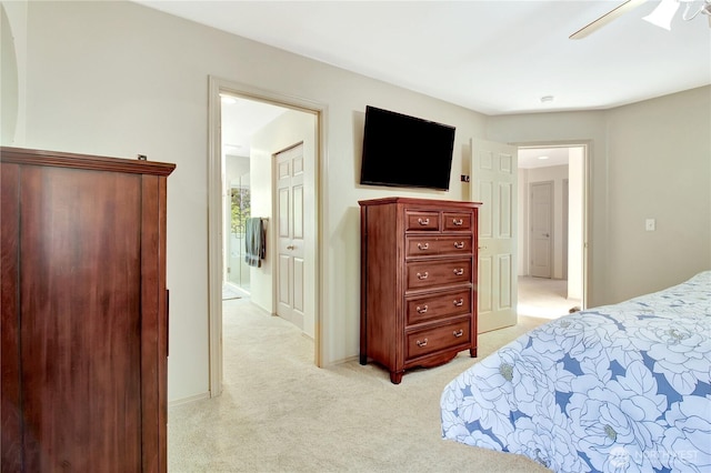 bedroom featuring a ceiling fan, light colored carpet, and ensuite bathroom