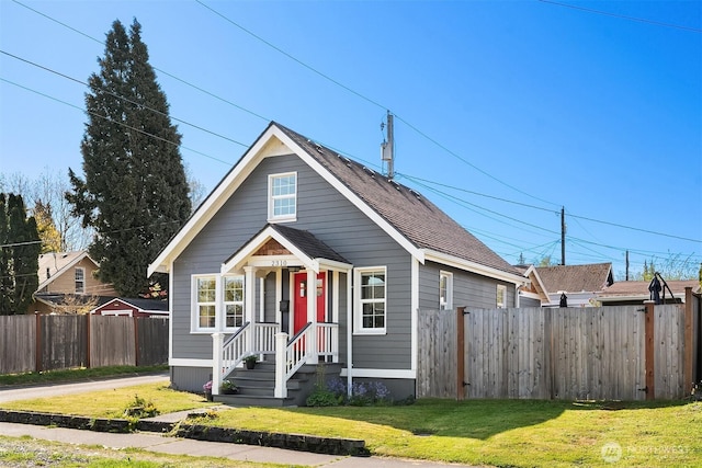 bungalow featuring a front lawn and fence