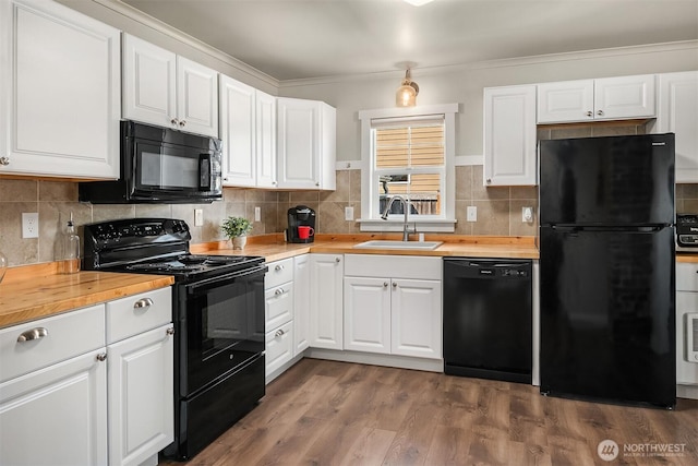 kitchen featuring a sink, wood counters, white cabinets, and black appliances