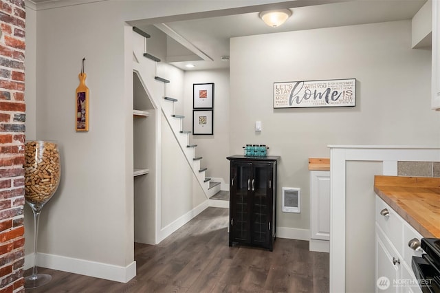 interior space with stairs, baseboards, visible vents, and dark wood-style floors