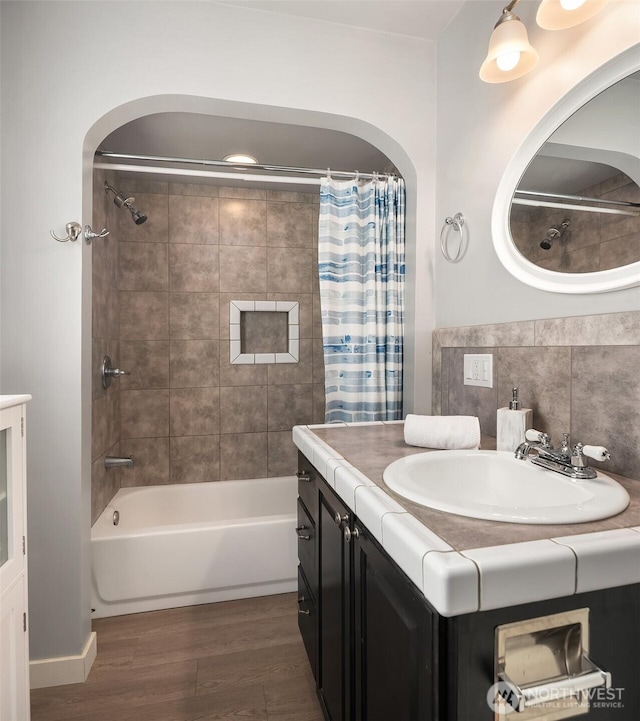 bathroom with shower / bathtub combination with curtain, wood finished floors, and vanity