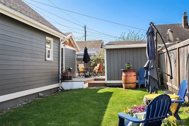 view of yard featuring a deck, fence, and an outbuilding