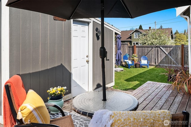 view of patio featuring an outdoor structure, a wooden deck, a shed, and a fenced backyard