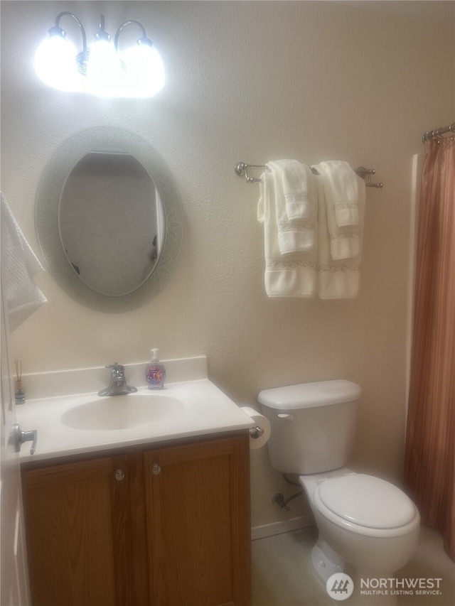 bathroom with toilet, baseboards, and vanity